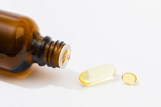 Close up of  oil filled capsules suitable for: fish oil, omega 3, omega 6, omega 9,  vitamin A, vitamin D, vitamin D3, vitamin E  and glass vial- Image