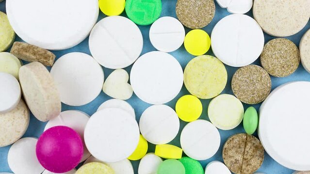 Assorted pharmaceutical medicine pills, tablets and capsules over blue background