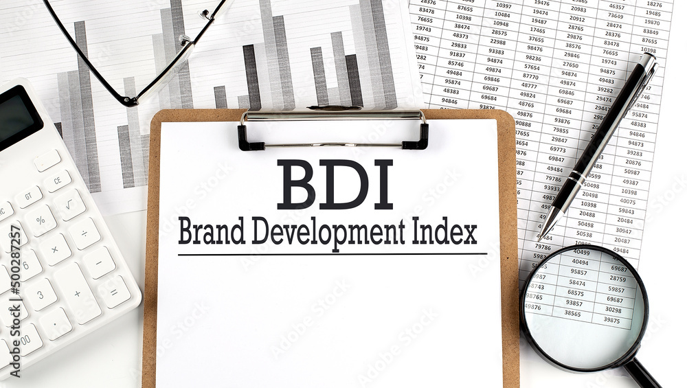 Poster paper with bdi acronym for brand development index on a chart with calculator,pen and magnifier