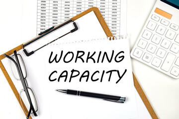 Text WORKING CAPACITY on the white paper on clipboard with chart and calculator