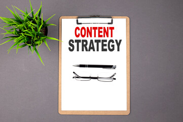 CONTENT STRATEGY on the brown clipboard on the grey background. Business concept