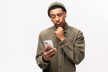 Portrait of man holding chin, standing with smartphone in hand, contemplating about software...