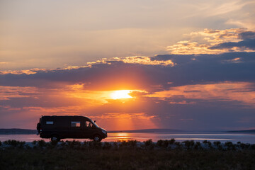 Fototapeta na wymiar Backlighting silhouette of a camper next to a salt lake at sunset