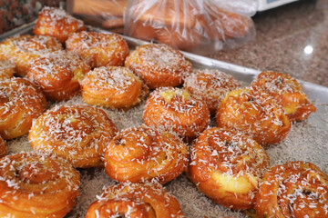 Sweet bun rolls covered with white coconut at display in local Jordan bakery, closeup detail