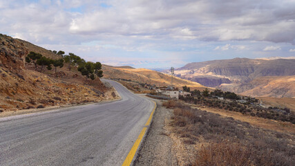 Road in mountainous terrain near At Tafilah, Jordan, Dead Sea at distant background