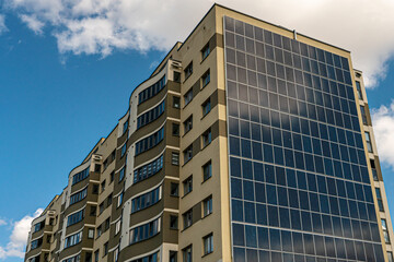 Fototapeta na wymiar Movement of clouds against the background of a modern energy-efficient building. Multi-storey residential building with solar panels on the wall. Renewable energy in the city