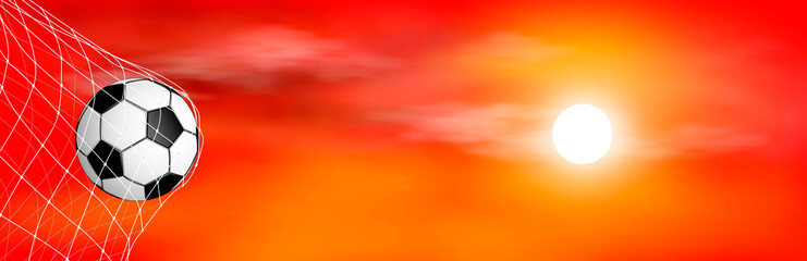 Soccer ball at sunset. The soccer ball is in the goal net. Soccer ball on the background of the sunset. Red background