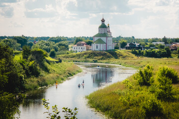Summer landscape in Suzdal. Church of Elijah the Prophet on the bank of the river Kamenka. Tourists...