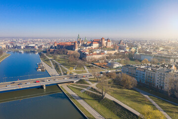Fototapeta na wymiar Krakow Poland. Grunwaldzki bridge at Vistula river, Wawel castleat the background. Sunny morning sunlight. Aerial city view from above