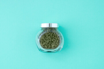 Green tea in a glass jar with lid. Turquoise background.