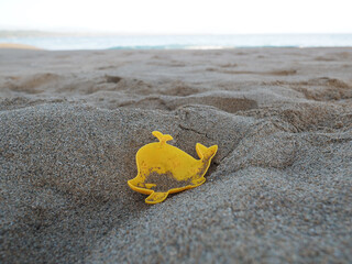 Yellow whale toy on tropical beach in sand..