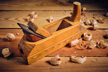 Old wooden carpenters tool plane on a wooden background.