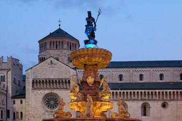 Illuminated Fountain of Neptune in the colors of the Ukrainian flag in front of Trento Cathedral in the Square Piazza Duomo in Trento, Italy