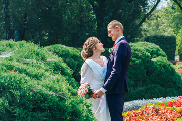 Newlywed couple in love.Stylish bride and groom are walking through a summer green park.