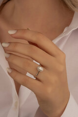 Beautiful lady's hand. woman wearing a white blouse and a diamond ring on her finger.