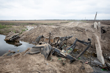 A blown up bridge and burnt out civilian cars in a place where the Russian and Ukrainian armies recently fought in Kyiv region, Ukraine.