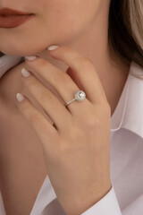 Beautiful lady's hand. woman wearing a white blouse and a diamond ring on her finger.