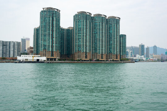 Group Of Green Skyscrapers By The Sea And Hong Kong City Behind