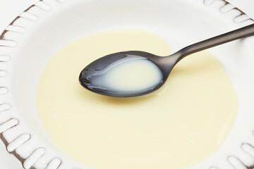 Transparent honey pouring down from wooden spoon with walnuts on a black background. Shallow depth of field
