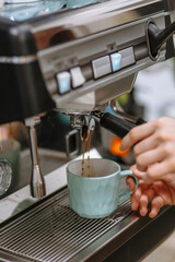 A barista girl pouring coffee from a coffee machine into a cup. Cafe