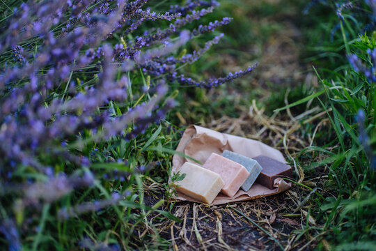 Natural cosmetic. Zero waste concept. Choice plastic free eco products. Hand holding natural solid hand soap bar on background of summer herbage grass.