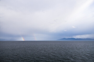 Naklejka na ściany i meble Storm clouds and rainbow over the ocean