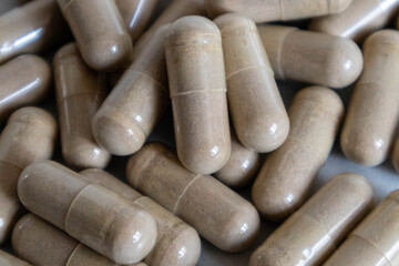 Many oblong capsules of brown color on a light background close-up
