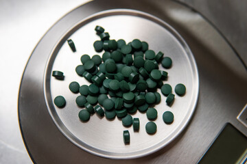 spirulina tablet macro photo on male hand.