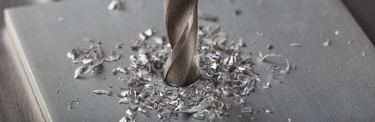 metal drill bit make holes in aluminium plate on industrial drilling machine. Metal work industry.
