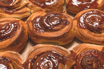 Homemade cinnamon buns with spices and caramel on parchment paper.