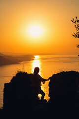 Silhouettes of a girl against the background of the sea and the setting sun