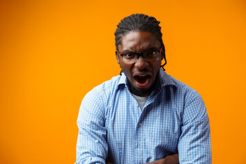 Handsome black man shouting against yellow background in studio