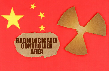 On the flag of China, the symbol of radioactivity and torn cardboard with the inscription Radiologically controlled area