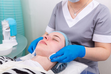 Obraz premium The cosmetologist treats the skin of the face with a tonic