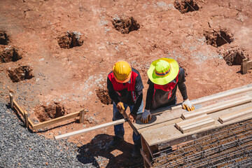 Two unrecognizable people cutting wood at a construction site on a sunny day