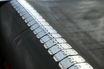 Close-up of a rubber conveyor belt connected by a flexible metal joint.Selective focus.