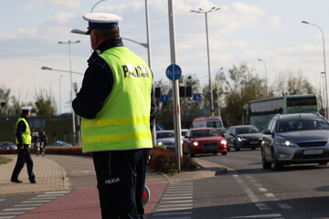  Policjant policji drogowej podczas kierowania ruchem z lizakiem do zatrzymywania pojazdów. - obrazy, fototapety, plakaty