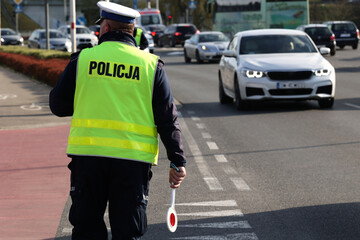  Policjant policji drogowej podczas kierowania ruchem z lizakiem do zatrzymywania pojazdów. - obrazy, fototapety, plakaty