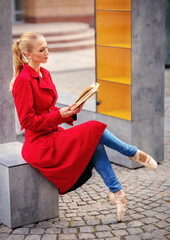 Ballerina dancing and reading book in the city street. inspiration concept