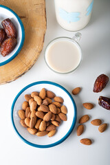 Almond milk in glass with almonds and red dates. Top view.