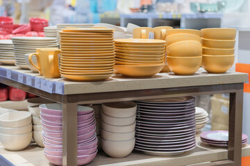 Dishes are sold at the store. Rows of different yellow bowls and plates for home on shelves in a supermarket.