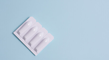 Suppository for anal or vaginal use on a blue background. Candles for treatment of hemorrhoids,...