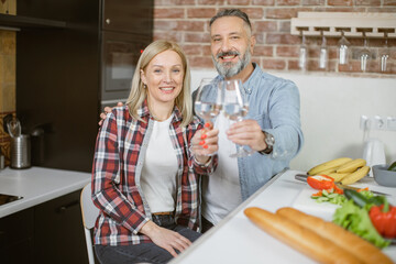Portrait of middle aged couple in love smiling and looking at camera while holding in hands glasses of fresh water. Happy family enjoying healthy their healthy lifestyles