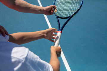 Instructor teaches proper grip on tennis racquet - obrazy, fototapety, plakaty