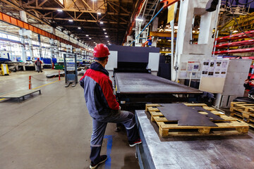 Worker works with metal sheet forming machine at the metalwork factory
