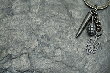 metal keychain with the coat of arms of Ukraine on the background of the black stone