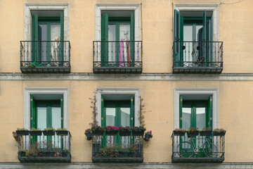 Six green balconies with plants and a mannequin on an old yellow facade
