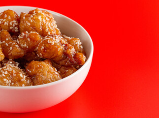 Bowl of Sesame Chicken on a Bright Red Background