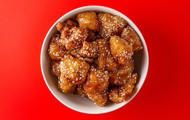 Bowl of Sesame Chicken on a Bright Red Background
