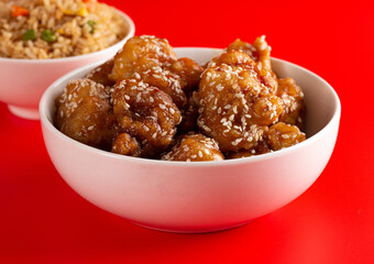 Bowl of Sesame Chicken on a Bright Red Background